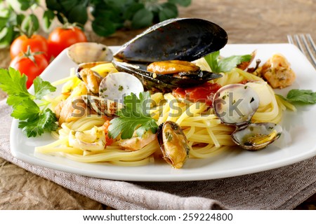 Spaghetti with salmon, clams and mussels on complex background
