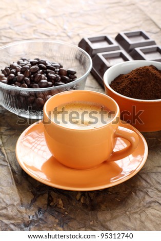 Cup of coffee with foam and coffee beans and ground coffee