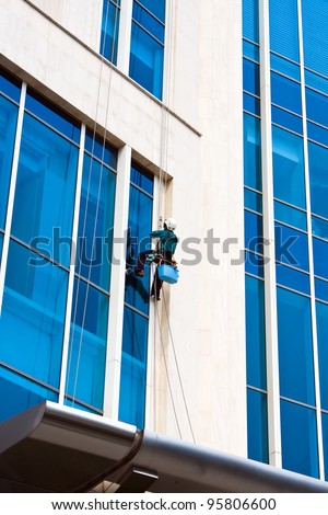Worker clean mirror on high building