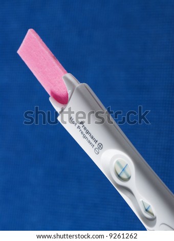 Pregnancy test device. Selective focus shot with dramatic lighting and blue background.
