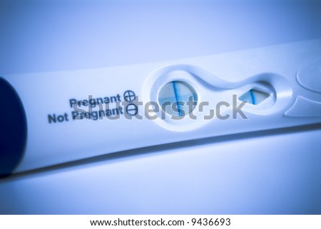 Pregnancy test device showing the positive result. Selective focus shot with dramatic blue lighting and intentional vignetting