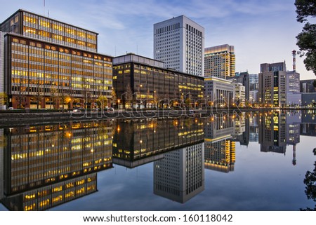 Tokyo, Japan buildings at the Marunouchi business district reflect on the Imperial Palace moat.