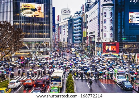 TOKYO, JAPAN - DECEMBER 15, 2012: Pedestrians sheild themselves from rain with umbrellas at Shibuya Crossing. The intersection is known as the busiest in the world.