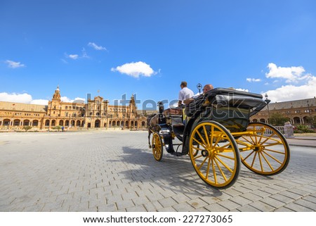 SEVILLE, SPAIN - OCTOBER 11, 2014: A horse drawn carriage tour through Spanish Square. The Horse drawn carriages are a popular way for tourists to visit the city.