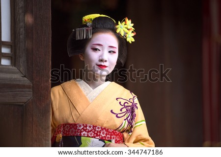 KYOTO, JAPAN - NOVEMBER 28, 2015: A woman in traditional Maiko dress looks out from a temple doorway.