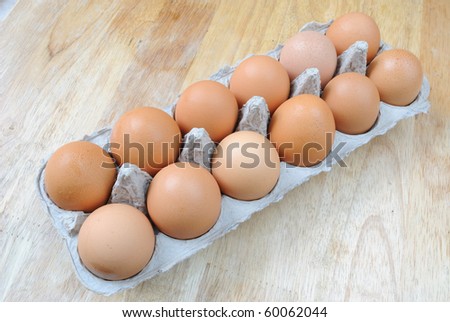 A carton of a dozen organic brown eggs on a wooden tabletop.