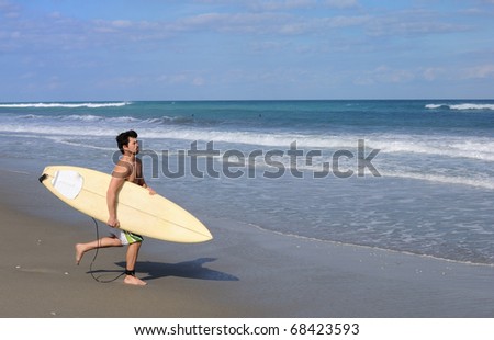Surfer running on the beach into the ocean with his board.
