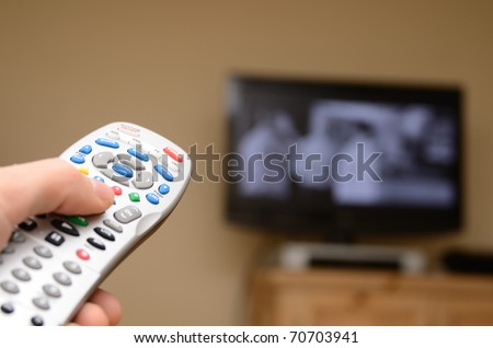 Television remote in the foreground with selective focus and television in the background.