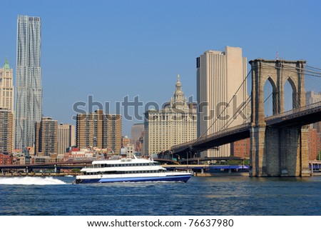 A river cruise boat on the East River heading under the Brooklyn Bridge in New York City.