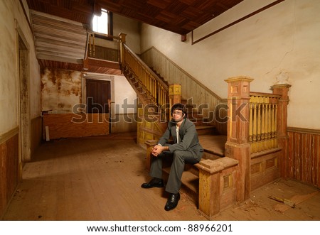 Man in suit sitting on the stairs of an old abandoned house.