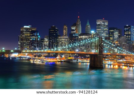 New York City skyline with the Financial District of Manhattan behind the Brooklyn Bridge at night.