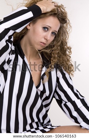 Young woman in referee black and white striped shirt over white background