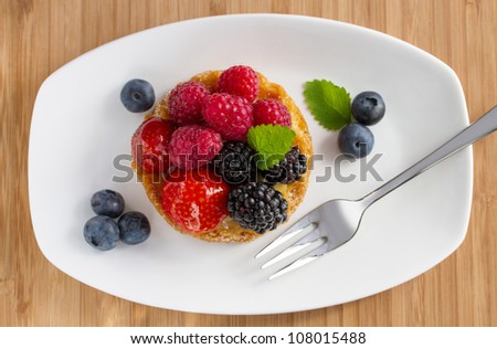 fruit cake with berries  on white plate with a fork