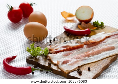 Food ingredient for the breakfast - sliced bacon eggs and pepper on cutting board.