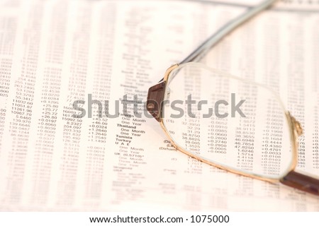 Eyeglasses on top of a financial newspaper with currency exchange rates
