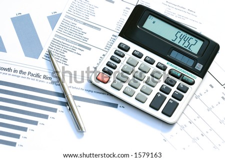 A calculator and pen on top of financial reports. Focus on displayed digits.