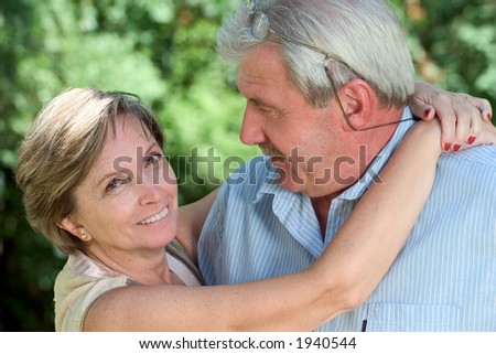 A woman in her fifties hugging her man and looking into the camera