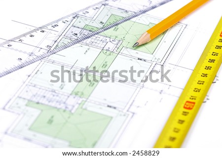 Pencil, tape measure and a ruler on top of a floor plan; Focus on pencil\'s tip.