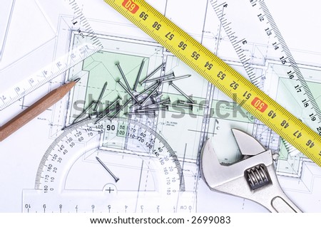 Above view of nails, monkey wrench and other tools on top of a floor plan.