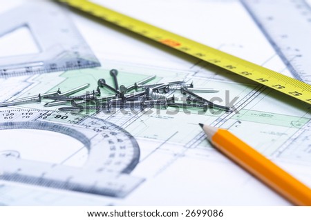 Pencil, tape measure, nails and geometric tools on top of a floor plan. Focus on nails.