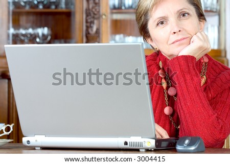 Middle-aged woman sitting in front of her notebook and looks at the camera