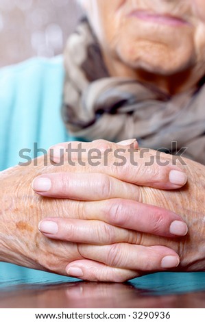 Elderly woman keeping her hands clasped, focus on hands