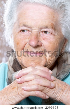 Elderly woman with hands clasped under the chin, looking away