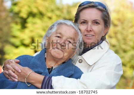 Middle-aged woman cuddles her elderly mother