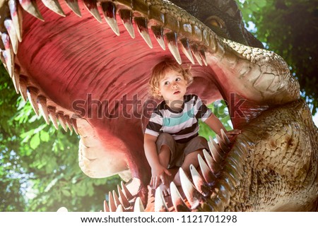 Little boy inside of a dinosaur\'s mouth in dino park