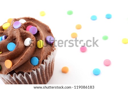 Mini chocolate cupcake with colorful sprinkles on white background