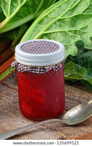 Fresh picked rhubarb stalks with homemade rhubarb jam on old wooden background