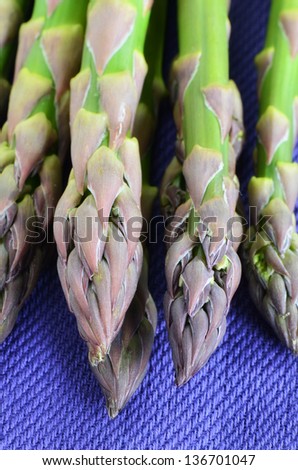 Fresh raw asparagus bunch closeup on purple napkin in vertical format