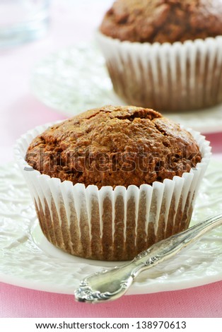 Bran muffins on cream colored rippled plates in vertical format