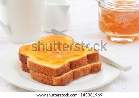 Toasted white bread with orange marmalade, white dishes, horizontal composition