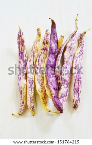 Bunch of purple Dragon\'s Tongue beans on white rustic board in vertical format