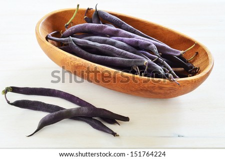 Bunch of purple queen wax snap beans in rustic bowl in horizontal format