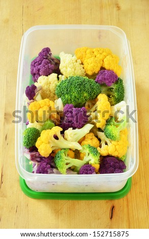 Tri color cauliflower pieces with broccoli in plastic container vertical format