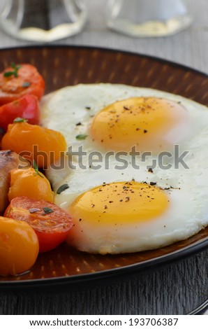 A hearty breakfast of fried eggs and cherry tomatoes with thyme garnish