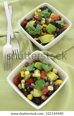 Black bean salad with avocado, corn, tomato, red onion and cilantro in vertical format