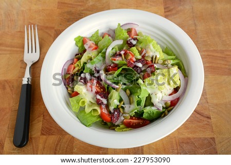 Fresh crisp romaine lettuce and cherry tomato salad with red onion and pumpkin seeds