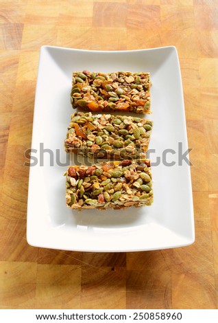 Gluten free almond apricot granola bars on white plate with cutting board background