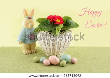 White wicker Easter basket with spring flowers, whimsical Easter bunny and eggs