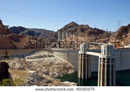 Hoover dam showing low water levels in Lake Mead reservoir, with the construction of the new bypass bridge in the background.