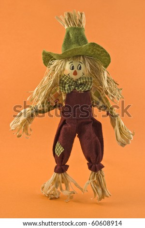 Corn husk scarecrow farmer doll on orange background in vertical format for Halloween or Thanksgiving theme