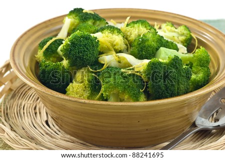 Steamed broccoli with lemon zest and Parmigiano Reggiano cheese in rustic yellow bowl