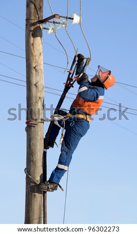 Electrician in blue overalls working at height