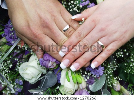 stock photo wedding rings on bride and grooms hands on top of flowers