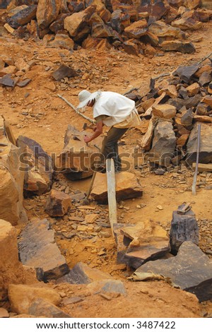 worker breaking rocks with hammer and chisel in a stone quarry
