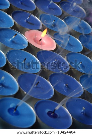 pink candle surrounded by blue candles with smoke conceptual