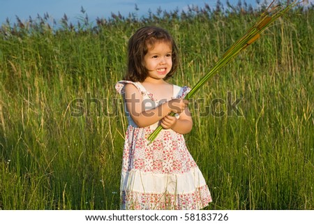 Happy little girl staying among the reeds